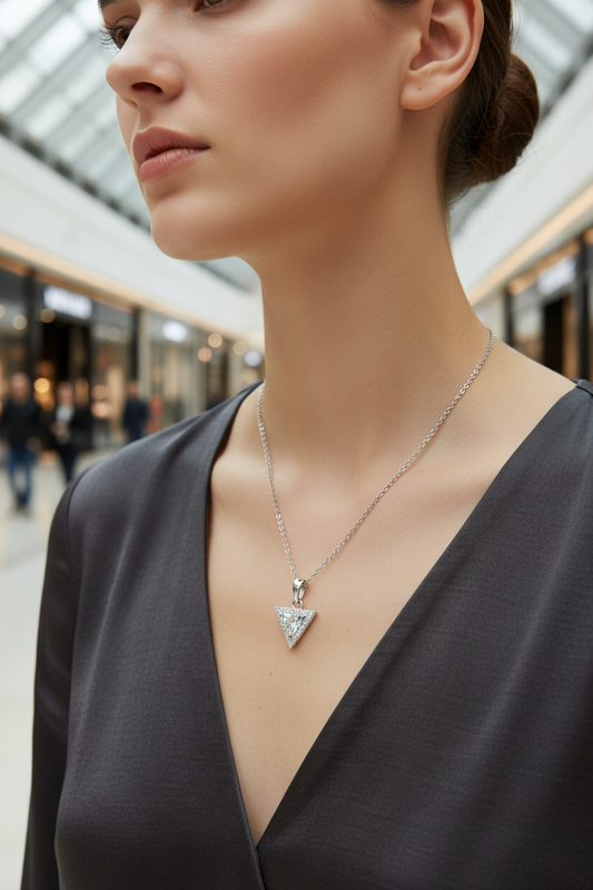 Woman wearing a necklace with a triangular pendant in an indoor setting