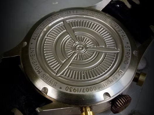 Close-up of a watch movement with engraved details on a metallic surface.