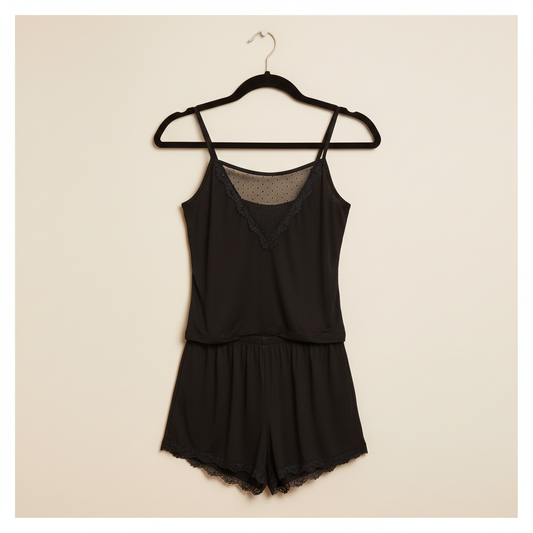 Black romper on a hanger against a beige background